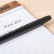 A Universal One black rollerball pen on a notebook.