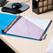 A light blue Avery binder with purple paper on a desk.