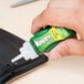 A hand using Krazy Glue to fix a cell phone.