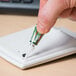A finger holding a Krazy Glue tube.