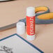 A Universal clear glue stick next to scissors.