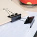 A Universal large black binder clip on a piece of paper.