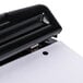 A black Universal 2 or 3 hole punch on a white sheet of paper.