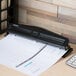 A black Universal 2 or 3 hole punch on a white countertop.