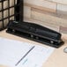 A Universal black countertop hole punch on a wood surface.