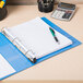 An Avery light blue heavy-duty non-stick binder on a desk with a pen and calculator.