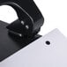 A Universal black countertop power assist 3 hole punch with white paper in it.