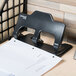 A Universal black countertop 3 hole punch on a table with paper.