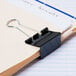 A black Universal binder clip on paper.