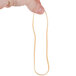 A hand holding a Universal beige rubber band.