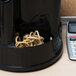 A black machine with a black container full of Universal beige rubber bands.