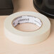 A Universal general purpose masking tape roll with a black label on a table.