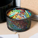 A black metal basket full of Universal assorted color vinyl-coated paper clips.