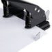 A black Universal 2 hole punch on a countertop with paper in it.