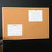 A Universal cork board with an oak frame with a calendar on it.