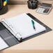 An Avery black heavy-duty view binder with a pen and calculator on a desk.