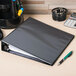 A black Avery heavy-duty view binder with a pen and calculator on a desk.