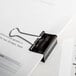 A piece of paper with a Universal black medium binder clip attached.