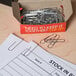 A box of Universal silver standard paper clips on a table with a piece of paper.