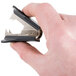 A person using a Universal black jaw style staple remover to remove a staple.