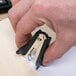 A hand uses a Universal black jaw style staple remover to open a piece of paper.