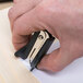 A person using a Universal black jaw style staple remover to remove staples from paper.