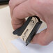 A person using a Universal black jaw style staple remover to remove staples.