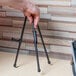 A hand holding a Universal black steel portable tabletop easel on a table.