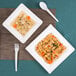 A white EcoChoice bagasse bowl filled with soup, vegetables, and rice on a place mat with a spoon.
