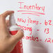 A hand holding a white and red Universal Dry Erase Spray Cleaner bottle.