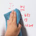 A hand wiping a whiteboard with a blue Universal microfiber cloth.