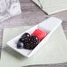 A white rectangular Tuxton china dish with raspberries on it.