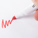 A hand holding a red Universal Desk Style Dry Erase Marker writing on a white sheet.