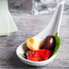 A Tuxton TuxTrendz bright white china tasting spoon filled with food on a table.