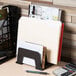 A black plastic Universal incline sorter with 5 sections holding a calculator and file folders.