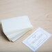 A white table with a stack of Universal clear laminating pouches next to a business card.