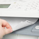A person's hand putting Avery Print-On white tabs into a printer.