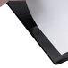 A hand holding a piece of paper over a black and white Universal non-stick binder.