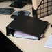 A black Universal economy non-stick binder on a desk with papers.