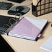 A black Universal economy non-stick binder with 3 rings on a table with a computer and pen.