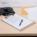 A brown Universal hardboard clipboard on a desk with paper and a pen.