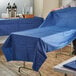 A man using a navy blue Hoffmaster table cover on a white table outdoors.