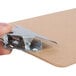 A hand holding a Universal brown hardboard clipboard with a metal clip.