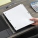 A person holding a white paper in Avery Legal Exhibit Dividers in a binder.