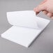 A person holding a Universal white scratch pad sheet.