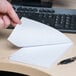 A person's hand holding a white Universal scratch pad sheet.