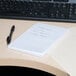 A Universal white unruled scratch pad on a desk with a pen.