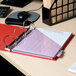 A red Universal economy non-stick binder on a desk with a pen and notebook.