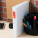 A white Universal Comfort Grip Deluxe Plus binder with pens in it.