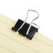 A black Universal Mini Binder Clip on a piece of paper.